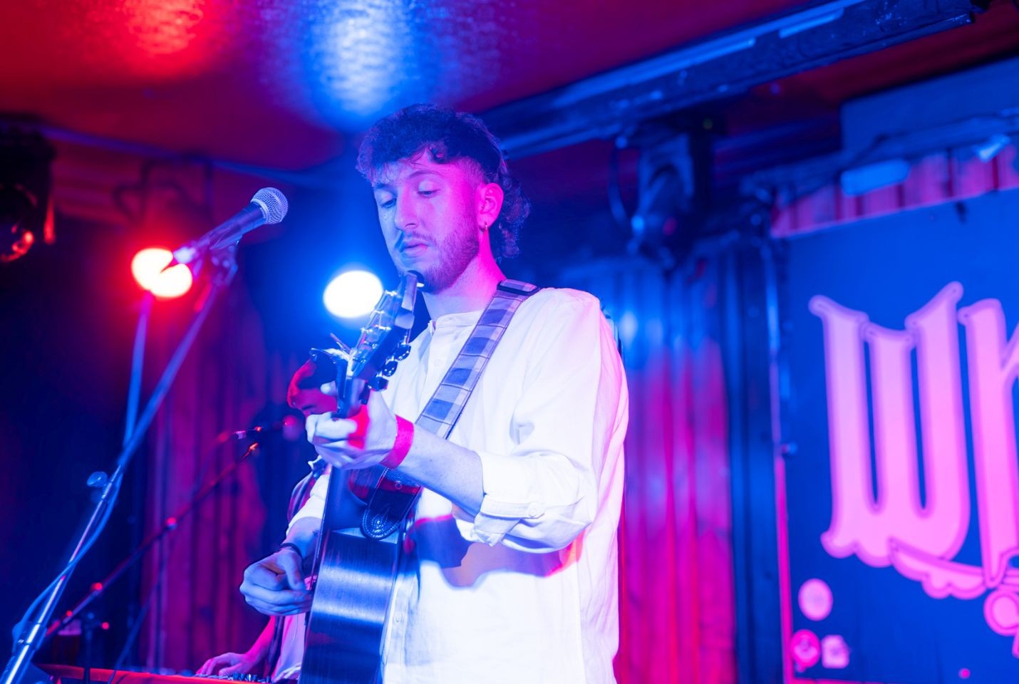 Jamie McIntyre performing at Whelans wearing a white shirt and holding a guitar